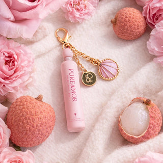 Pink skincare product with 2ml keychain and charms surrounded by pink roses on a textured surface
