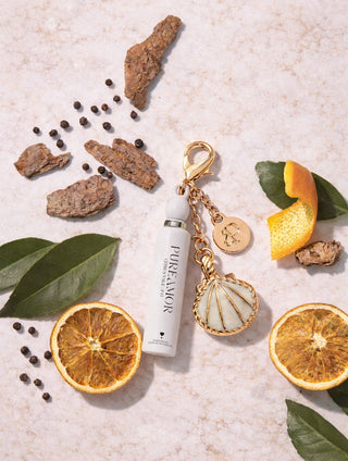 White 2ml keychain with gold keychain on a light surface with dried oranges and leaves.