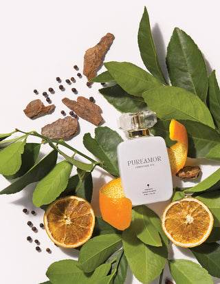 PUREAMOR 30ml perfume bottle surrounded by oranges, leaves, and spices on a white background
