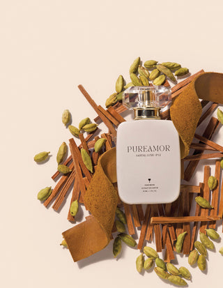 30ml Perfume bottle labeled 'PUREAMOR' surrounded by cardamom pods and cinnamon sticks on a beige background