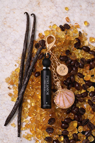 Perfume bottle labeled 'PURE AMOR' with vanilla beans, coffee beans, and amber on a textured surface. 2ml