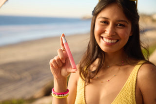 Woman holding 12ml travel spray on a beach