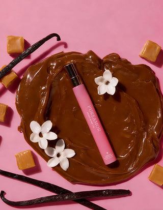 Pink 12ml travel spray lip balm with white flowers and chocolate on a pink background