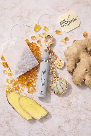 Pureamor 2ml keychain skincare product with ginger root and tea bag on a light background