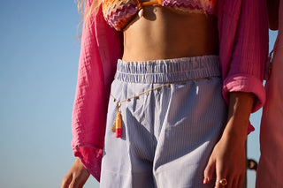 Person wearing a pink top and light-colored pants with a clear blue sky background and carrying 2ml keychain