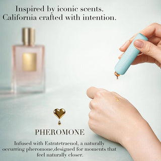 Hand holding a small device with a dropper, next to a perfume bottle, on a light gray background.
