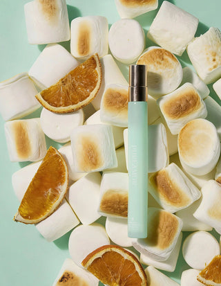 12ml travel spray surrounded by toasted marshmallows and orange slices on a light green background